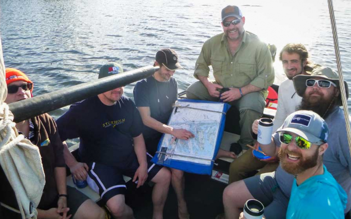 a group of veterans use a map to navigate on a sailing expedition 